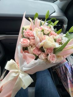 a bouquet of pink and white flowers in someone's lap with the steering wheel behind them