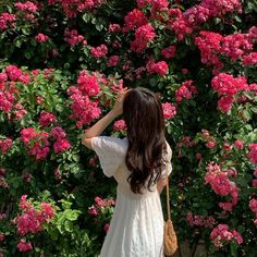 a woman standing in front of pink flowers