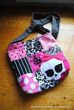 a pink and black patchwork purse with a skull on it, sitting on a cutting board