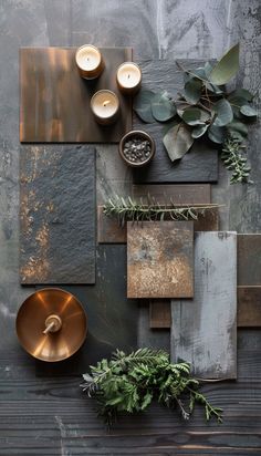 some plants and candles are on a wooden table next to a metal plate with a candle