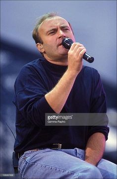 a man sitting in a chair holding a microphone to his mouth and looking up at the sky