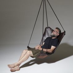 a man is sitting in a hanging chair