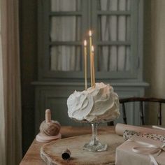 a cake sitting on top of a wooden table next to a pair of twin candles