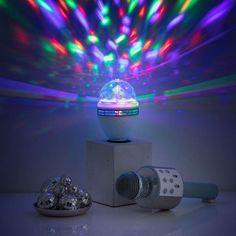 a disco ball sitting on top of a white block next to a speaker and bowl