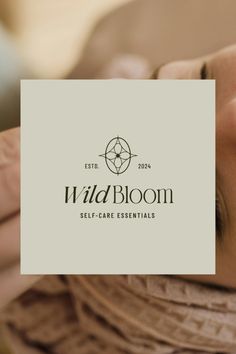 a woman holding up a business card with the words wild bloom on it in front of her face