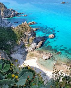 the beach is surrounded by green plants and clear blue water, with rocks on either side