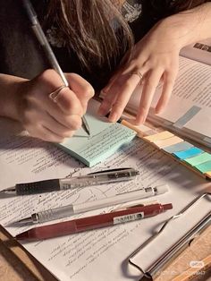 a person is writing on some paper with pen and ink rollers next to them