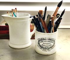 a cup filled with pens and pencils on top of a table