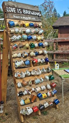 a wooden sign with coffee mugs on it in front of a fenced area