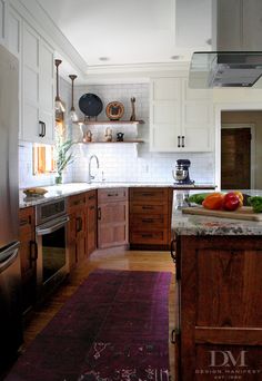 a kitchen with wooden cabinets and stainless steel appliances, along with a purple rug on the floor