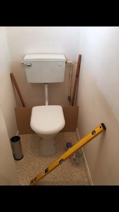 a toilet in a bathroom being remodeled with tape on the floor and some tools around it