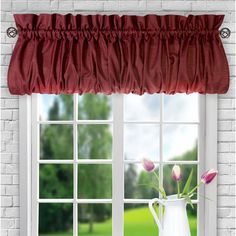 a vase with tulips in front of a window