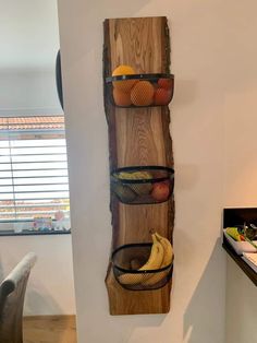 a wall mounted shelf with three baskets filled with fruit