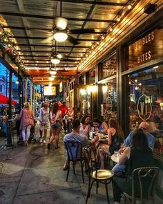 people are sitting at tables outside in the evening