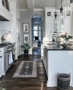 a kitchen with white cabinets and black counter tops, an area rug on the floor