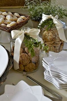 a table topped with plates and bowls filled with cookies covered in powdered sugars