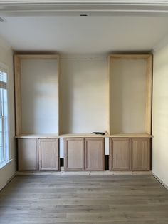 an empty room with wooden cabinets in the middle and hard wood flooring on the other side