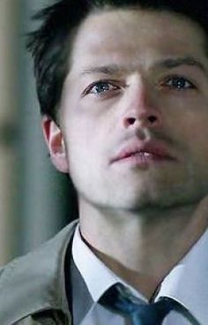 a man in a trench coat and tie looking off to the side with his eyes wide open