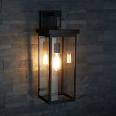 two light bulbs are attached to the side of a wall mounted lantern in a dark room