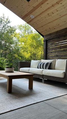 a couch sitting on top of a wooden floor next to a table with pillows in front of it