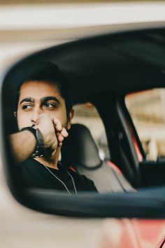 a man sitting in the passenger seat of a car holding his hand up to his face