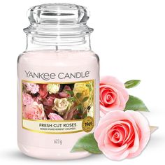 a pink candle with roses next to it on a white background and the words yankee candle fresh cut roses