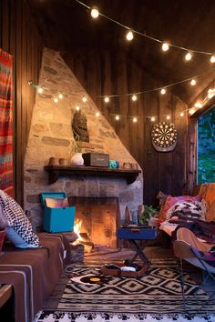 a living room filled with lots of furniture and lights hanging from the ceiling over a fire place