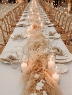 a long table with white plates and candles