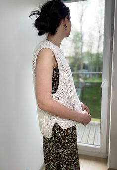 a woman standing in front of a window with her hand on her hip and looking out the window