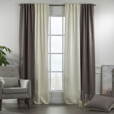 a living room filled with furniture and a large window covered in white drapes next to a chair