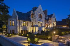 a large house with many windows and lights on it's side walk at night