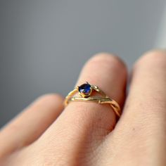 a woman's hand holding a gold ring with a blue stone on the side