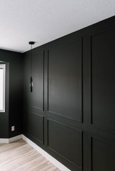 a room with black painted walls and white trim on the wall, there is a large window