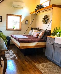 a bed sitting on top of a wooden floor next to a table and chair in a room