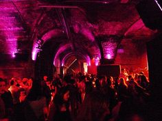 a group of people standing around in a room with purple lights on the ceiling and walls