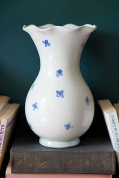 a white vase sitting on top of a stack of books