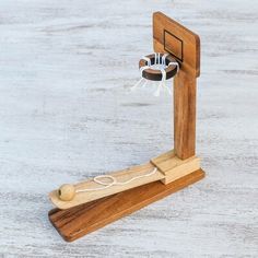 a wooden toy basketball hoop with a ball on the rim and net attached to it