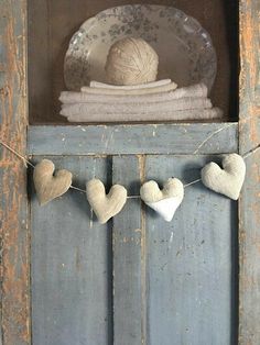 some hearts are hanging on a string in front of an old door with a ball of yarn