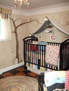 a baby's room with a tree mural on the wall and a crib