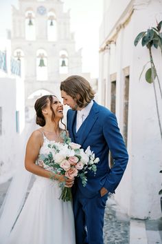 a bride and groom standing in front of a church