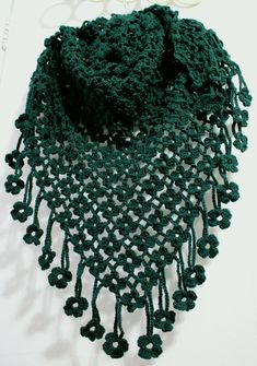 a green crocheted scarf is laying on a table