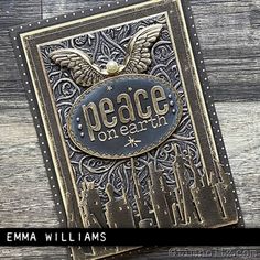 a card with the words peace on earth written in gold and black, sitting on top of a wooden surface