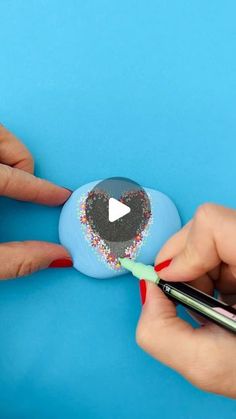 someone is painting an egg with sprinkles on it and holding a marker