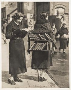 an old photo of two women looking at books on a street side stand, with the caption in russian