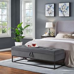 a bedroom with gray walls and white bedding in the center, along with a grey ottoman