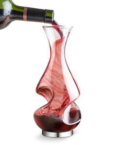 a wine bottle being poured into a glass with red liquid in front of white background