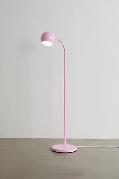 a pink lamp sitting on top of a table next to a white wall and floor