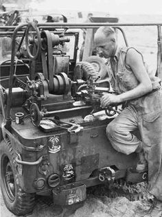 an old black and white photo of a man working on a machine in the mud