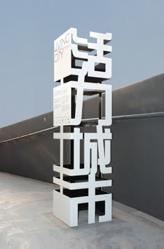 a white sculpture sitting on top of a cement floor next to a building with chinese writing