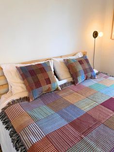 a bed with two pillows on top of it next to a night stand and lamp